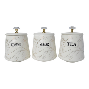 Three white ceramic kitchen canisters with gold marble design and gold handles, each labelled with different contents: coffee, sugar, and tea.